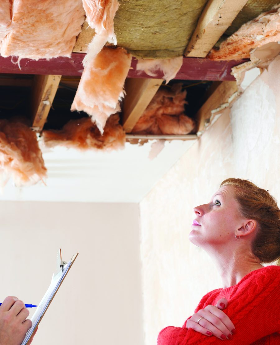 A homeowner looking up at a damaged ceiling