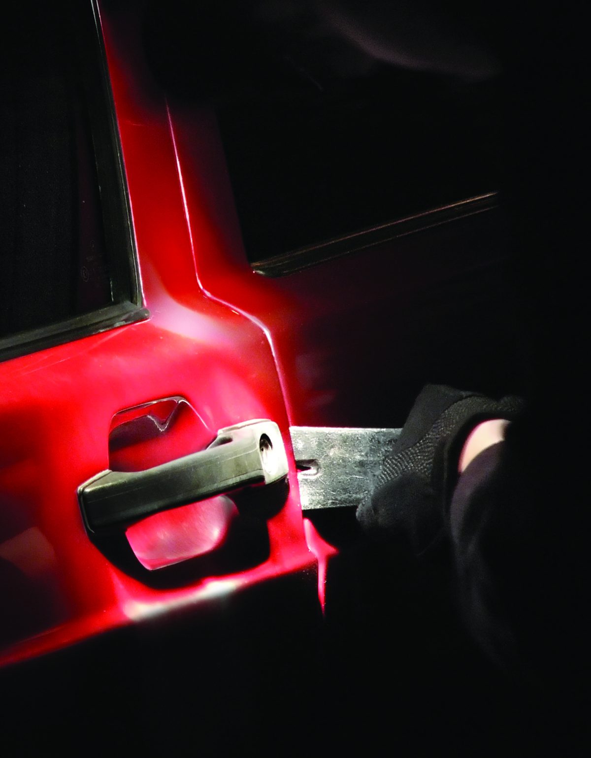 A thief forcing open a van door at night